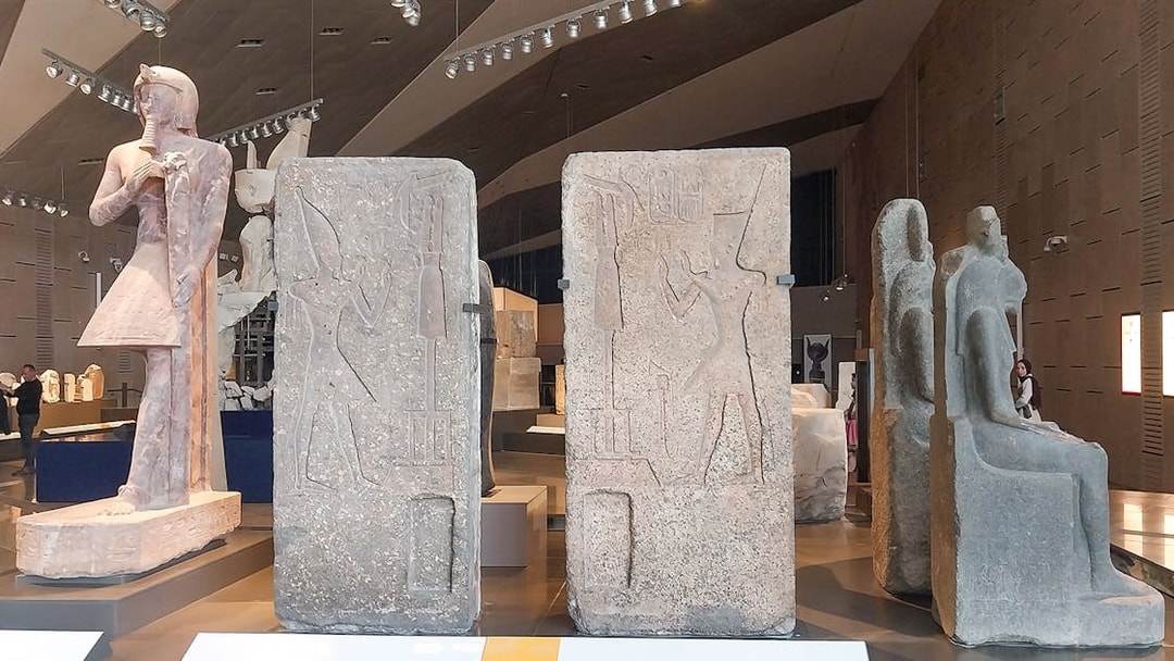 Ancient Egyptian statues and carvings inside the Grand Egyptian Museum.