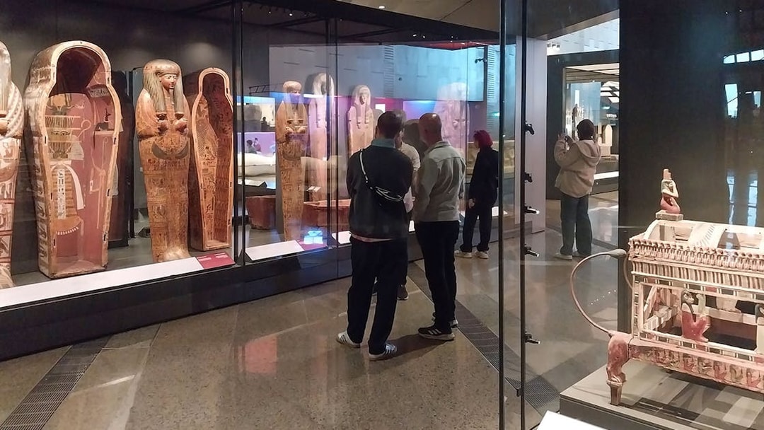 Visitors viewing ancient Egyptian sarcophagi at the Grand Egyptian Museum.
