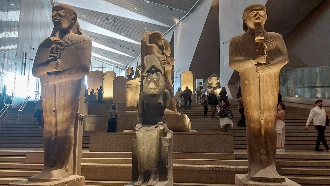 Statues inside the Grand Egyptian Museum with visitors exploring the exhibits.