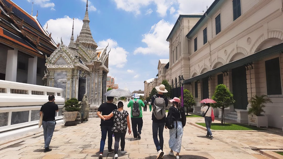 Visitors walking near ornate temple structures at Grand Palace, Bangkok.