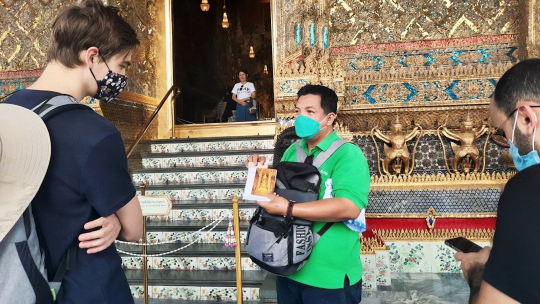 Tour guide explaining details at Grand Palace entrance, Bangkok.