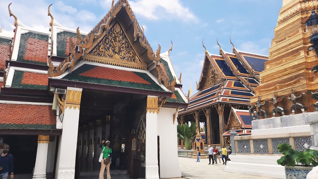 Grand Palace and Wat Phra Kaew buildings with tourists exploring the temple grounds in Bangkok.