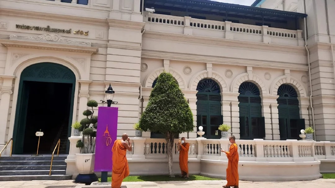 Monks in orange robes outside a building at the Grand Palace, Bangkok, during a walking tour.