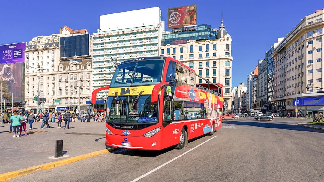 Buenos Aires hop-on hop-off tour bus in city center with historic buildings.
