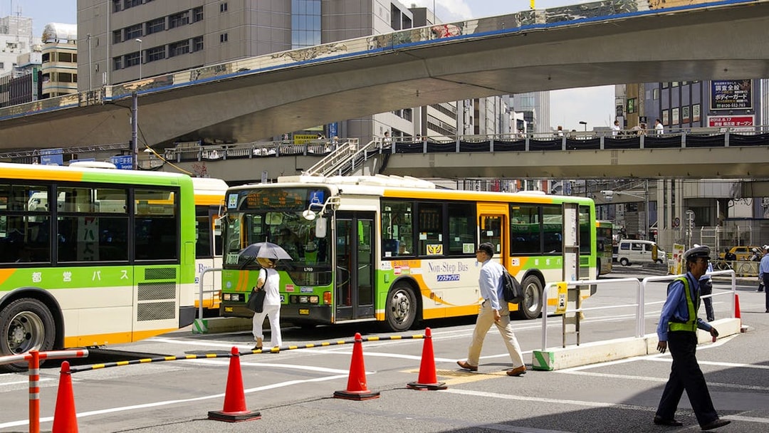 Tokyo city buses at a busy intersection, part of the Greater Tokyo Pass experience.