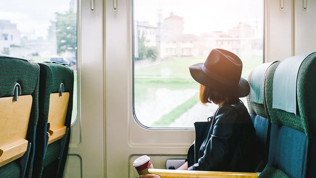 Woman on a train in Japan looking out the window at cityscape.