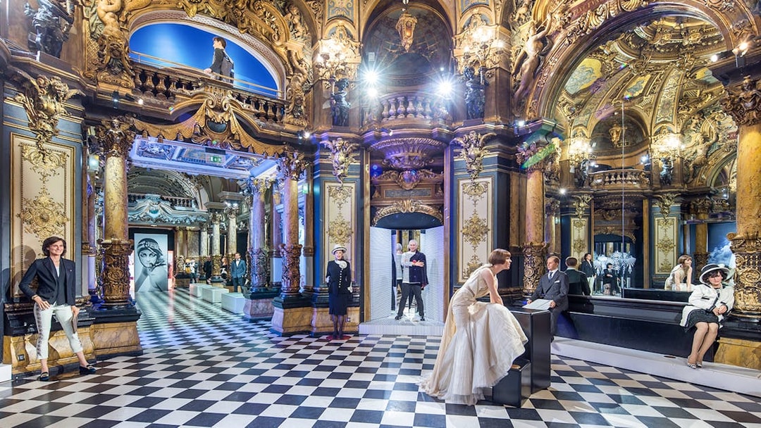 Grévin Paris wax museum interior with ornate decor and wax figures in elegant attire.