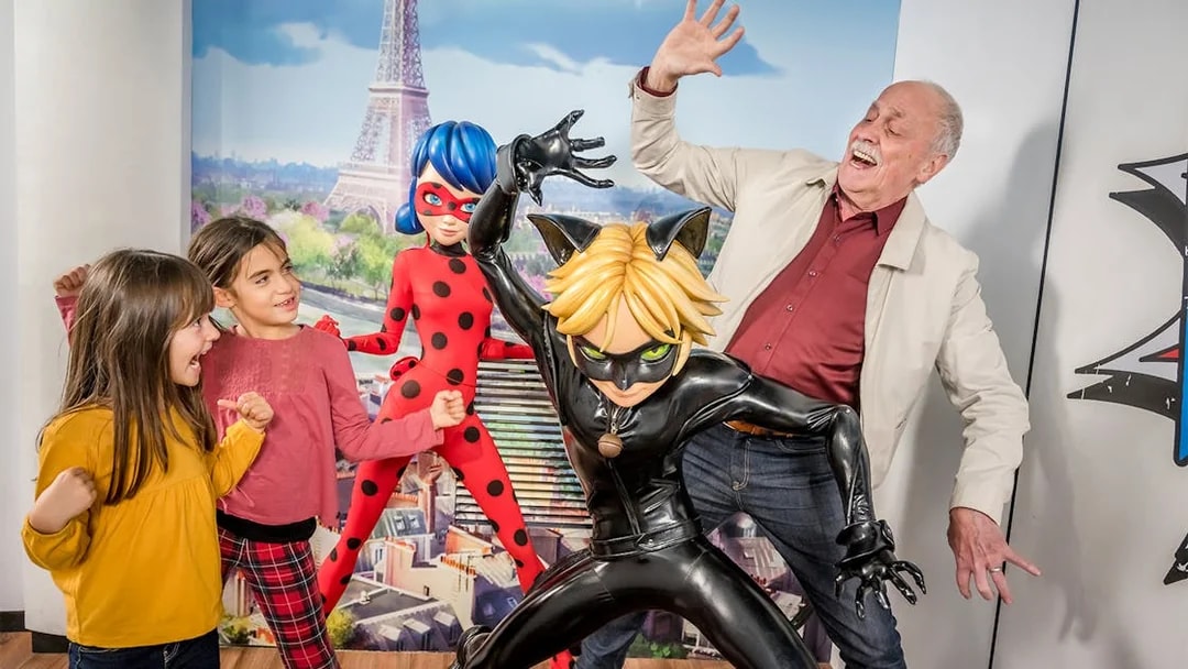 Visitors posing with Ladybug and Cat Noir figures at Grevin Museum, Paris.
