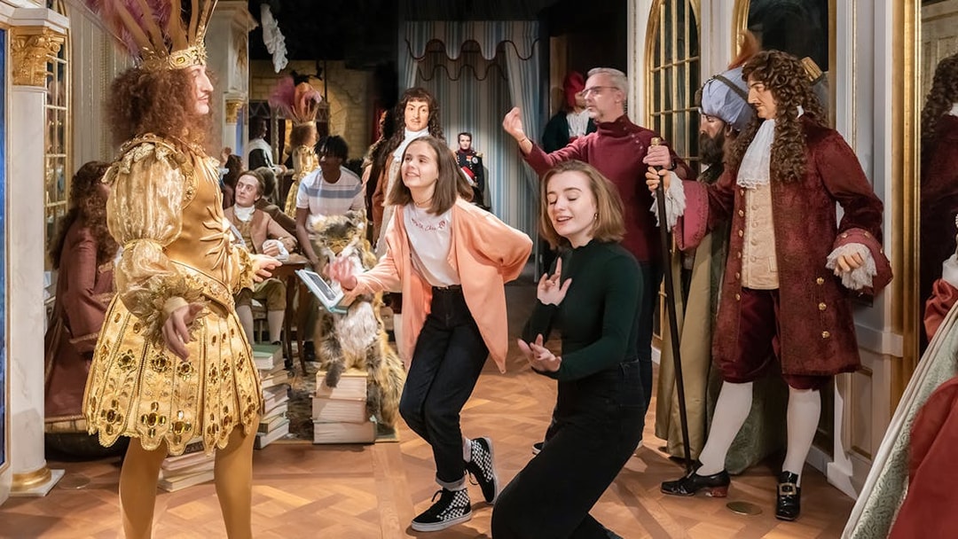 Visitors interacting with wax figures in historical costumes at Grévin Paris Wax Museum.