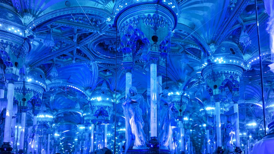 Grévin Paris wax museum hall with mirrored columns and blue lighting.