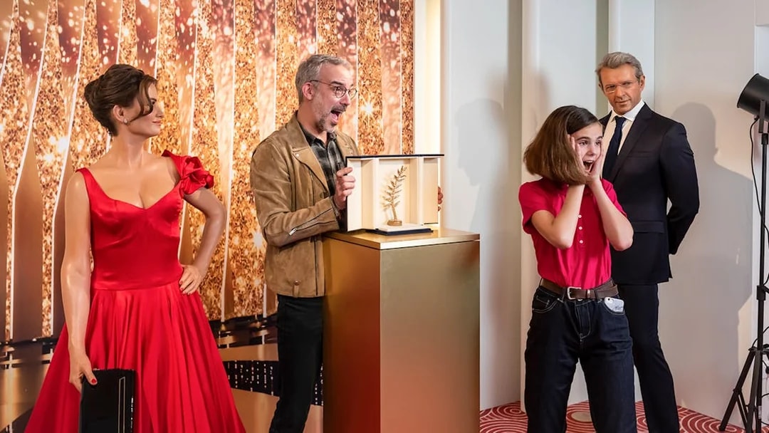 Wax figures at Grévin Paris with a girl reacting to a golden award display.