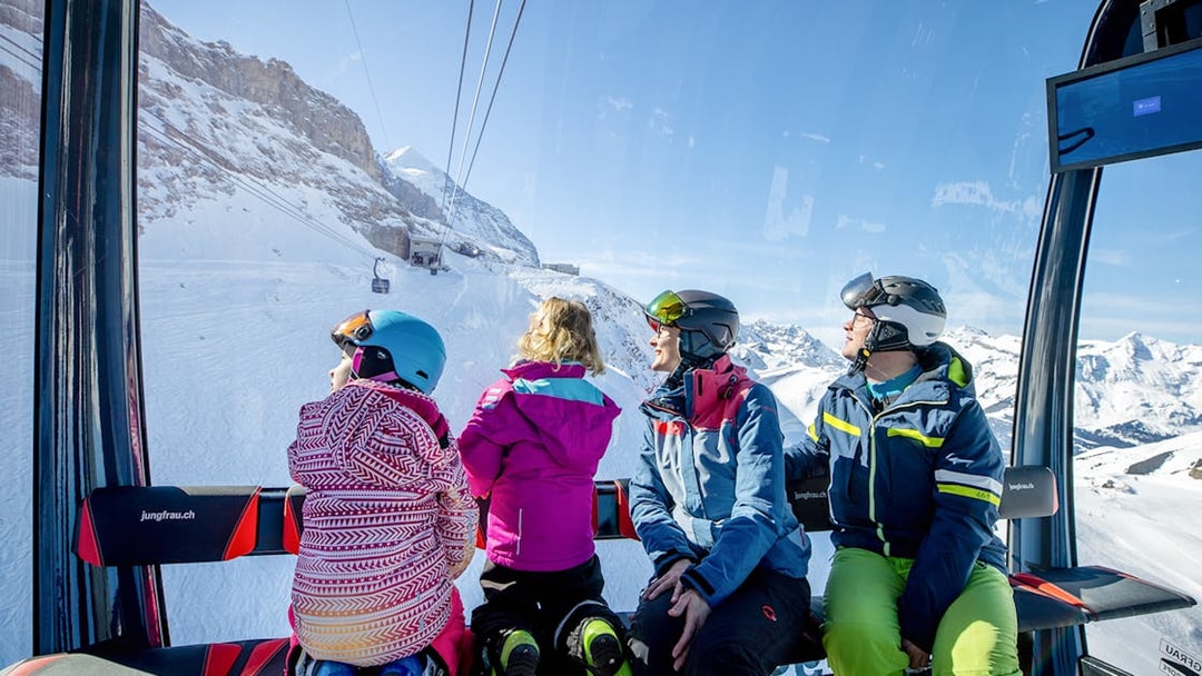 Family riding Eiger Express cable car with snowy Swiss Alps view.