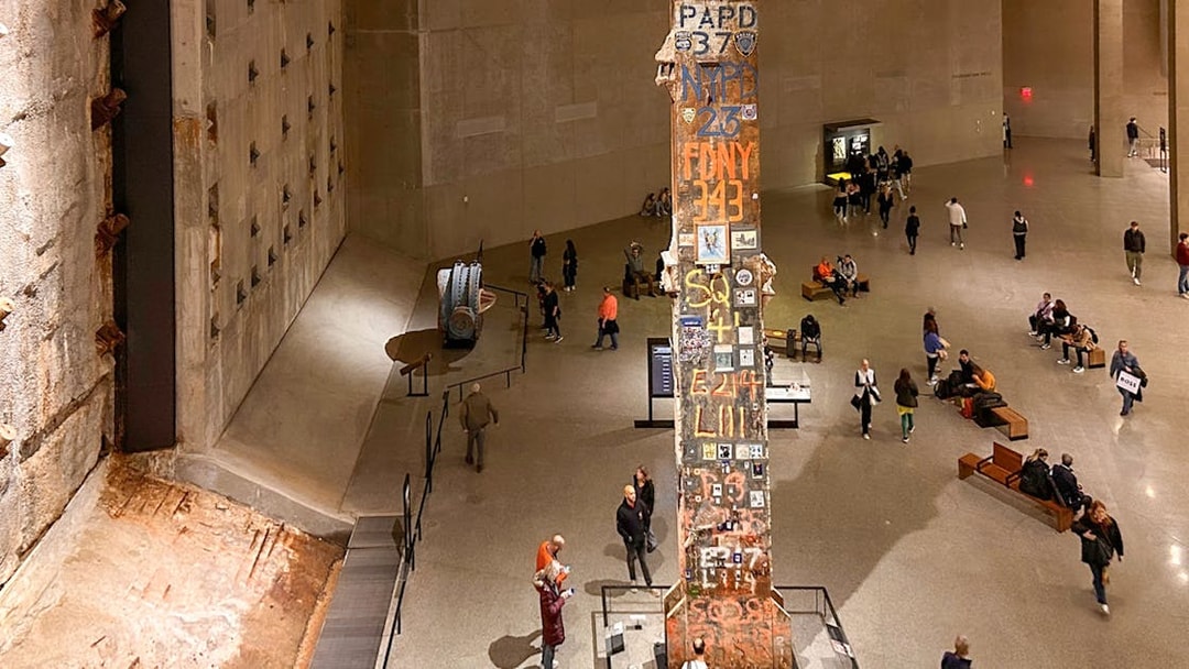 Final column at 9/11 Museum in New York City with visitors exploring exhibits.