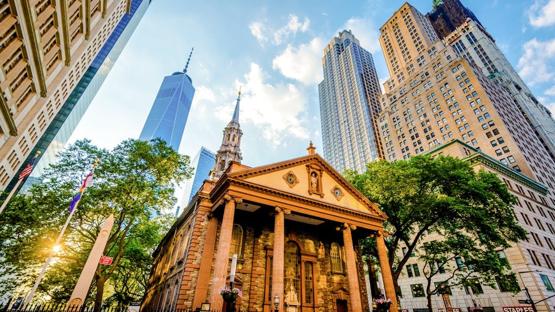 Saint Paul's Chapel at sunset with skyscrapers in Lower Manhattan.