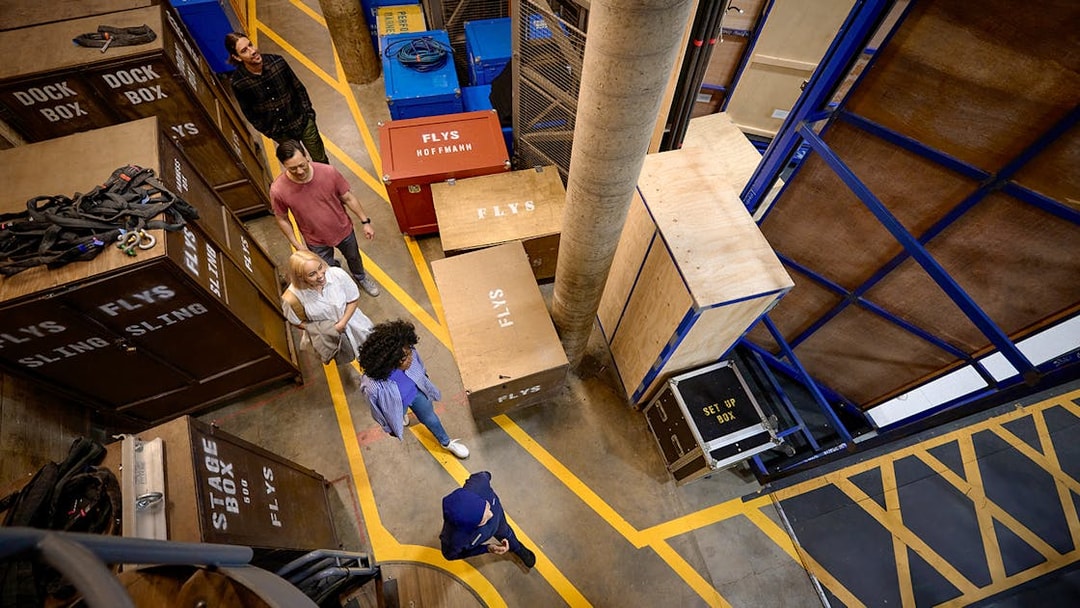 Visitors on a guided backstage tour of Sydney Opera House, walking among stage equipment.