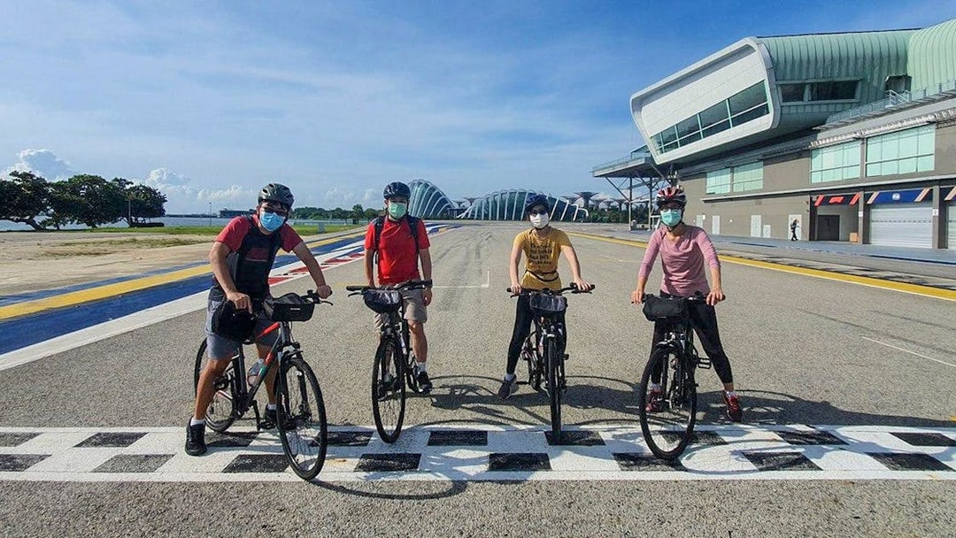 Cyclists on a track near modern architecture during Bike and Bites Food Tour.