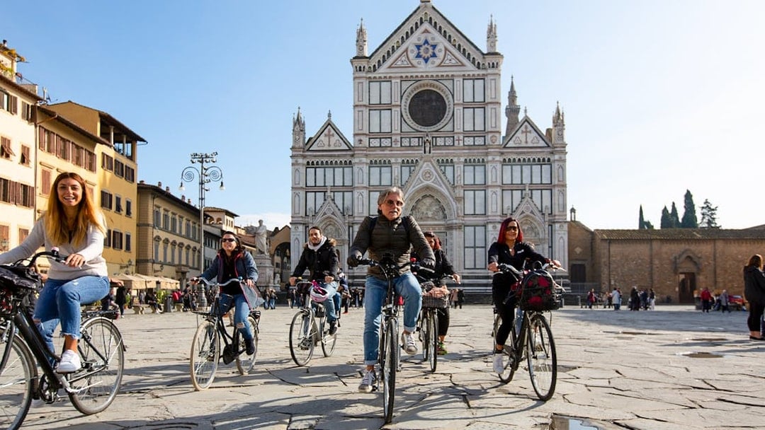 Cyclists riding in front of Basilica di Santa Croce, Florence.