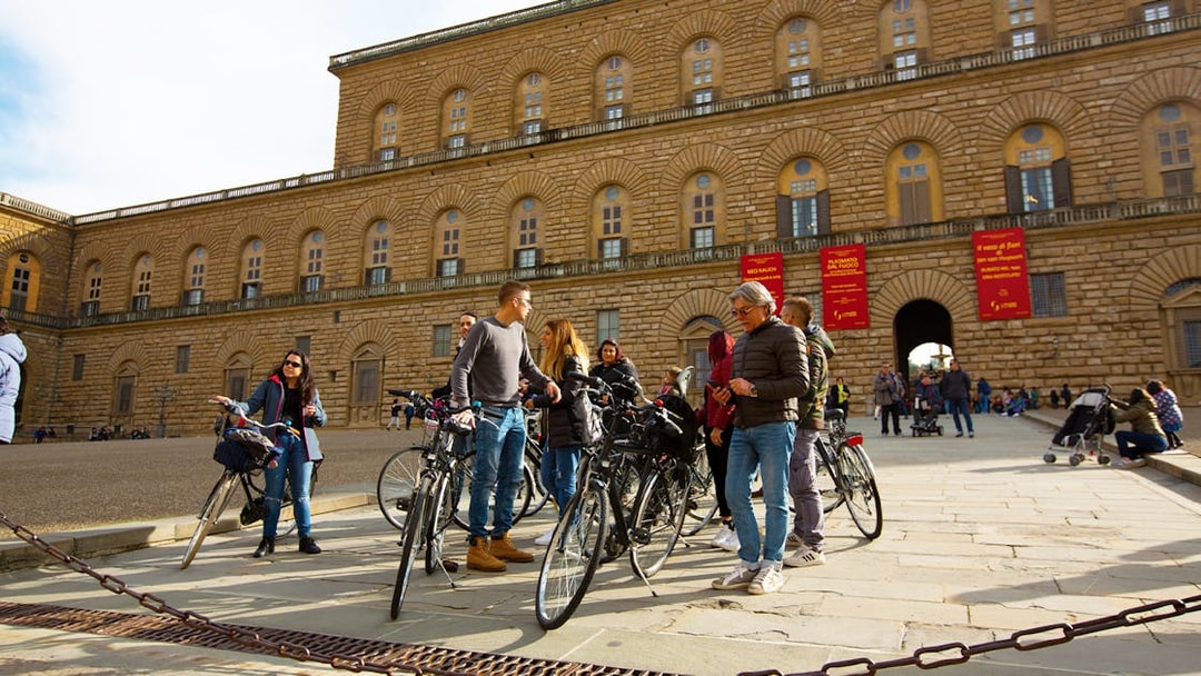 Cyclists gathered at Piazza Pitti in Florence, Italy, with the historic palace in the background.