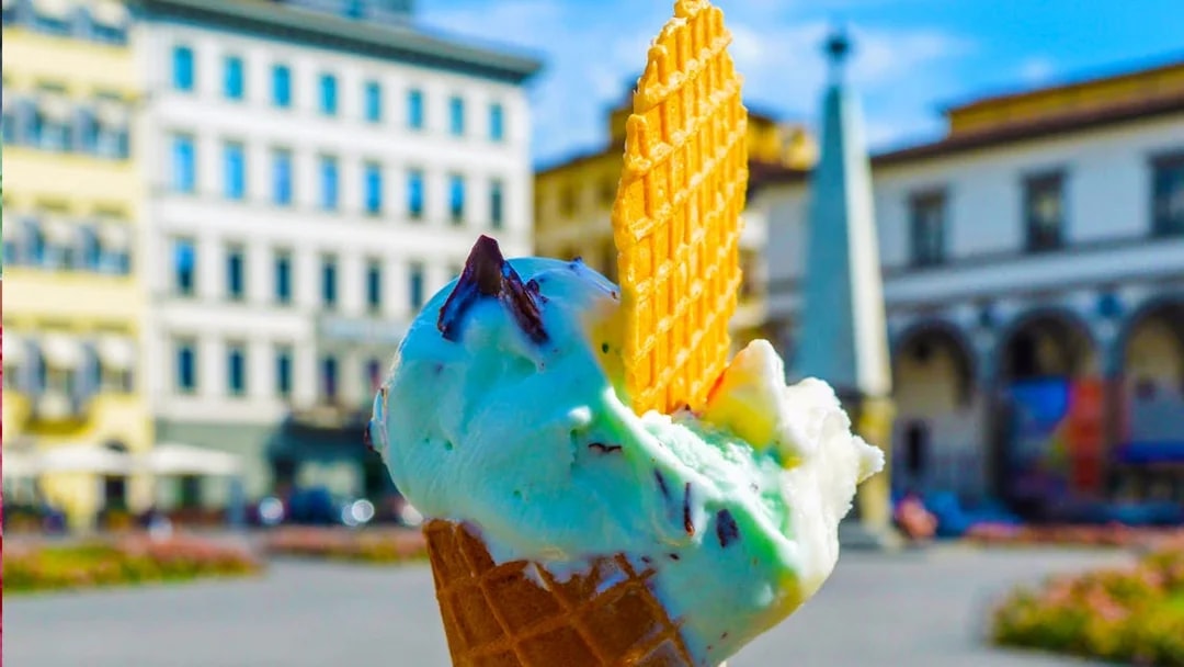 Gelato ice cream cone with wafer in a European city square.