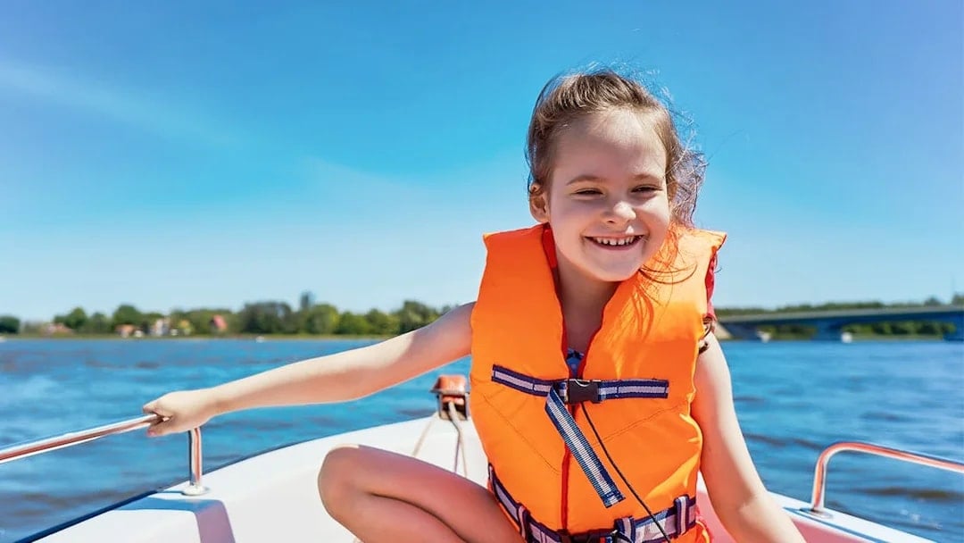 Child enjoying a guided boat tour in Dubai, wearing a life jacket.