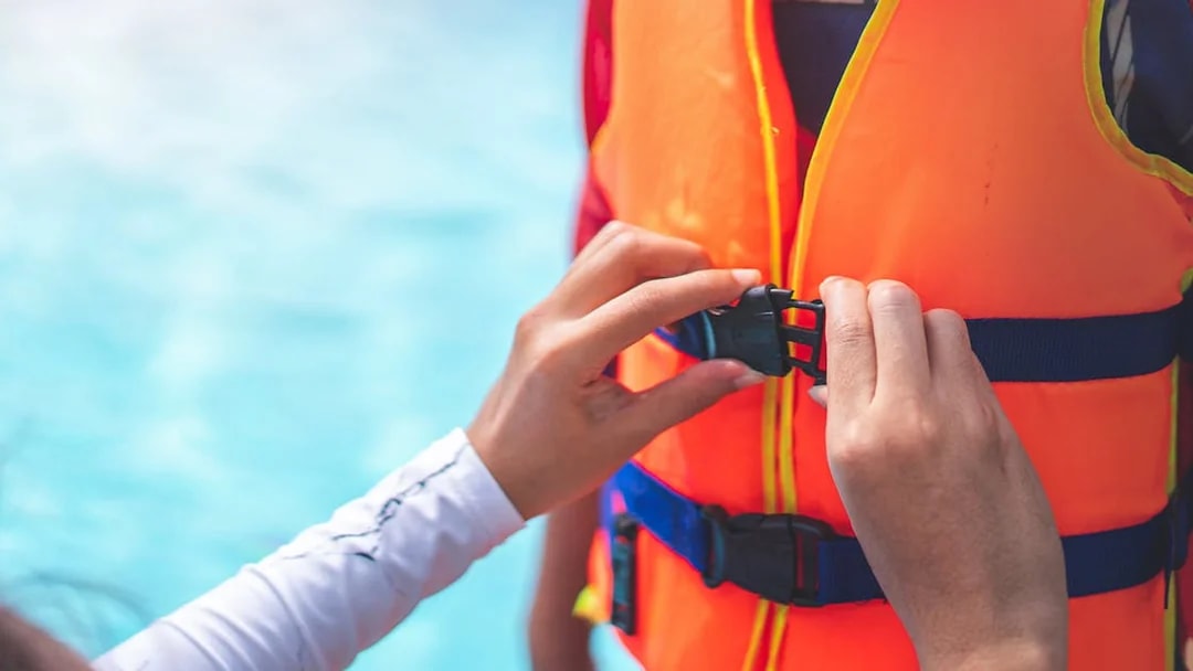 Person fastening a life jacket buckle for Black Boats Tours.