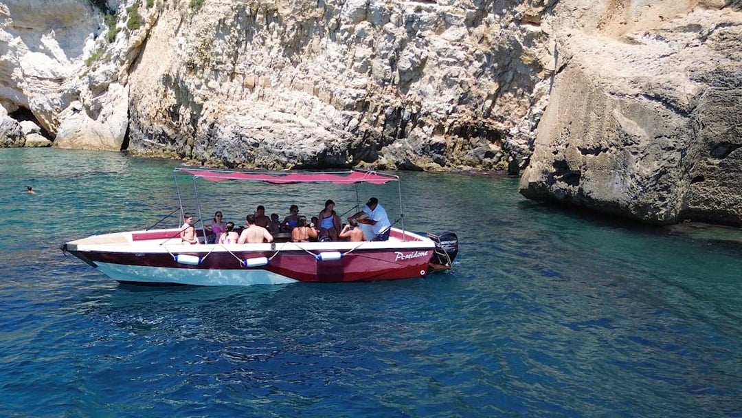 Boat tour at Ortigia Island Grotto with passengers near rocky cliffs.