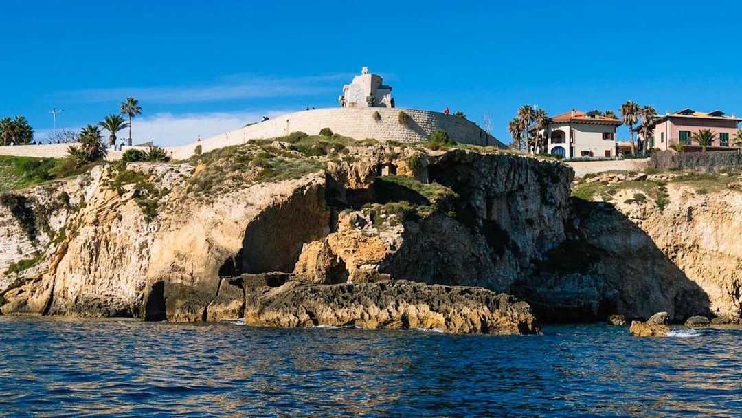 Cliffside view of Ortigia Island with historic buildings and sea caves.