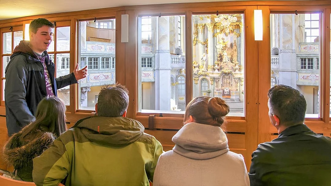 Tour guide explaining Frauenkirche interior to visitors on a gallery tour.