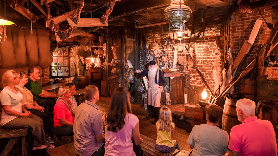 Group listening to a storyteller in a dimly lit room on the Savannah Ghosts & Gravestones tour.