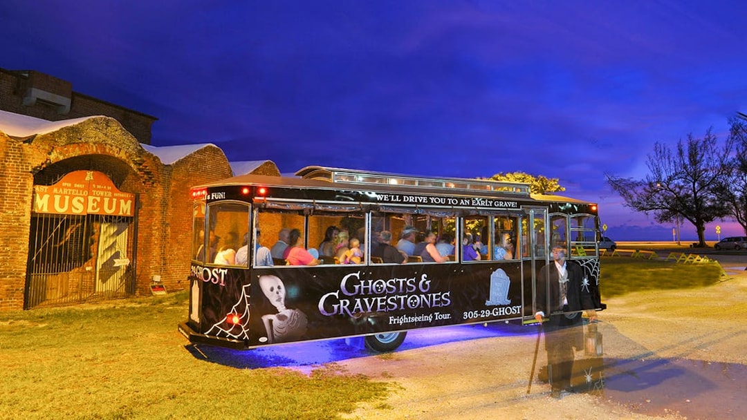 Guided trolley tour at night near Savannah museum entrance.