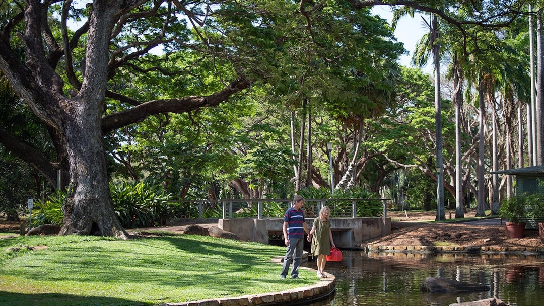 Couple walking by a pond in a lush park during a guided half-day city tour of Darwin.