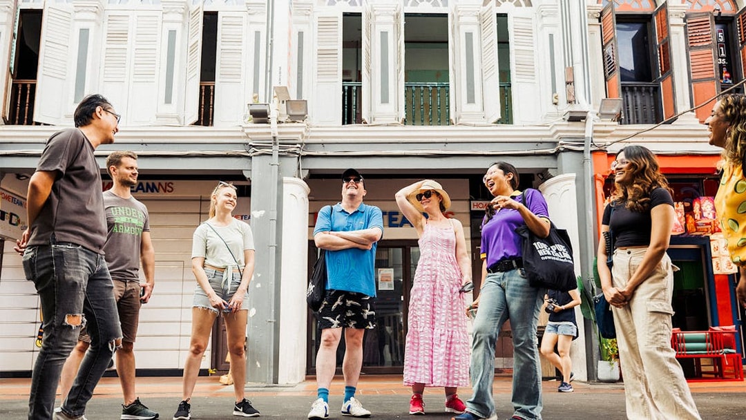 Group of tourists on a guided Michelin and local hawker food tour in a vibrant city street.