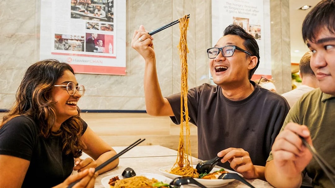 People enjoying noodles at a Michelin-rated hawker center during a guided food tour.