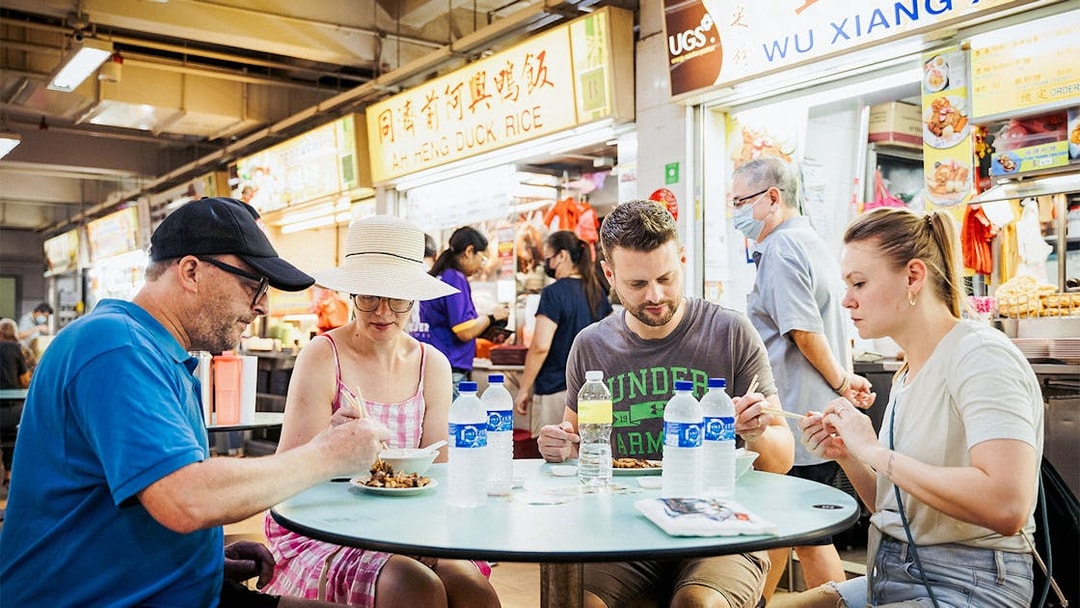 Group enjoying local dishes at a hawker center during a guided food tour.