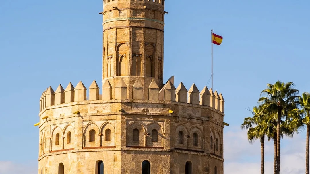 Torre del Oro with Spanish flag in Seville, part of a guided monumental walking tour.