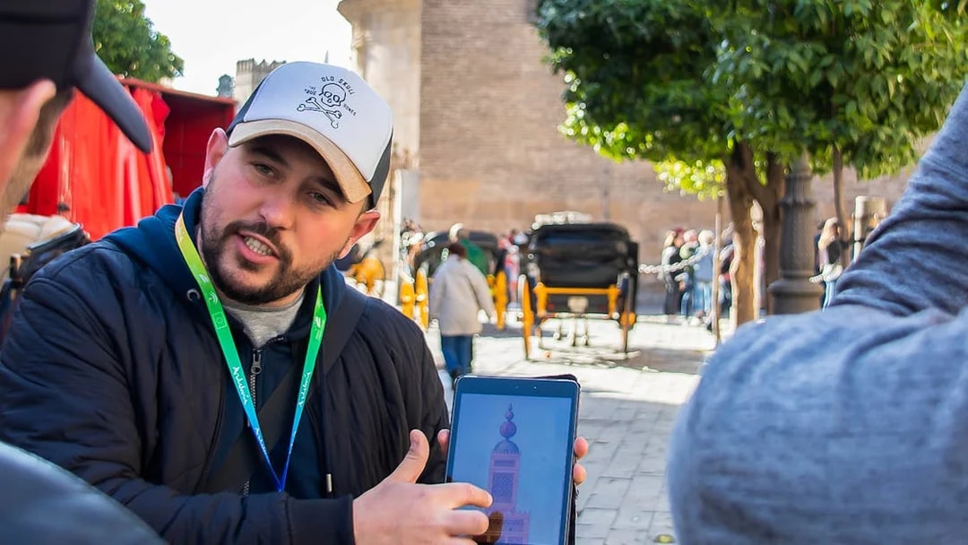 Tour guide showing a tablet with a monument image during a walking tour in Seville.