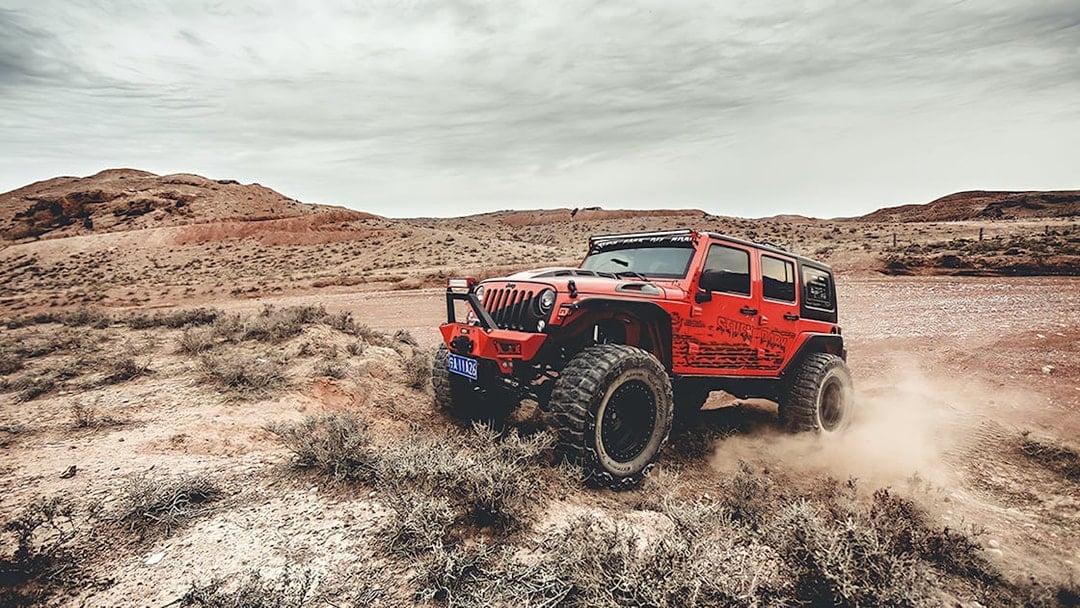 Red Jeep driving off-road in Cappadocia landscape during guided tour.