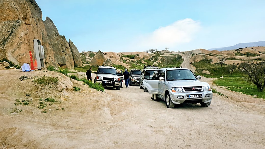 Off-road jeeps parked on a dirt path in Cappadocia with rocky landscape in the background.