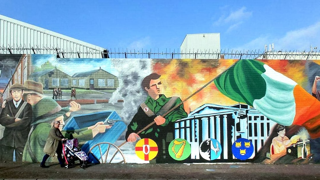 Belfast mural depicting historical political scenes and Irish flag on a guided taxi tour.