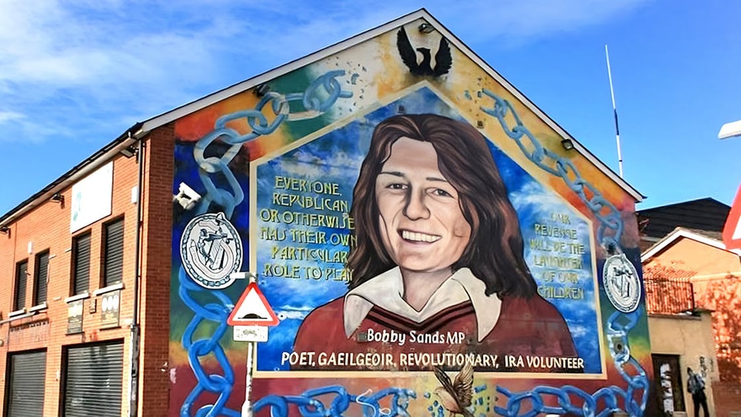 Belfast mural of Bobby Sands on a brick building, part of a guided political taxi tour.