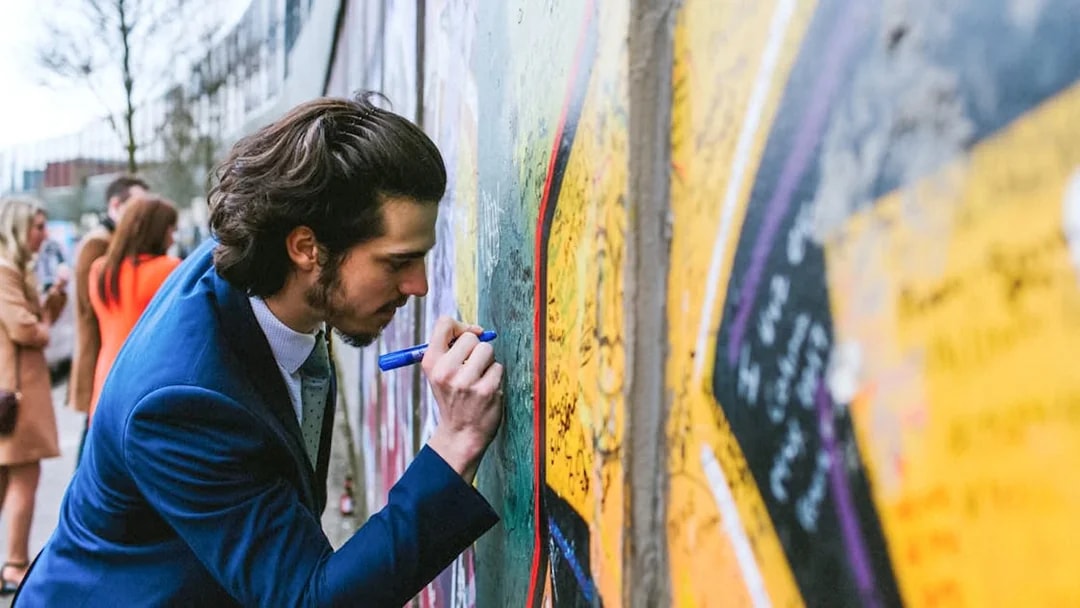 Man writing on Belfast Peace Wall during guided political taxi tour.