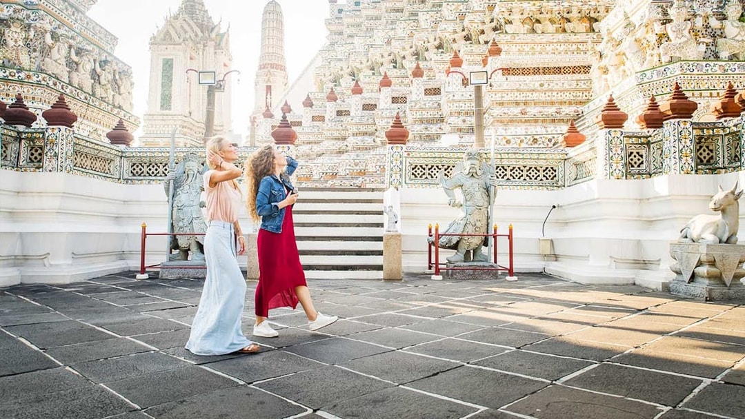 Visitors exploring ornate temple architecture at Grand Palace, Bangkok.