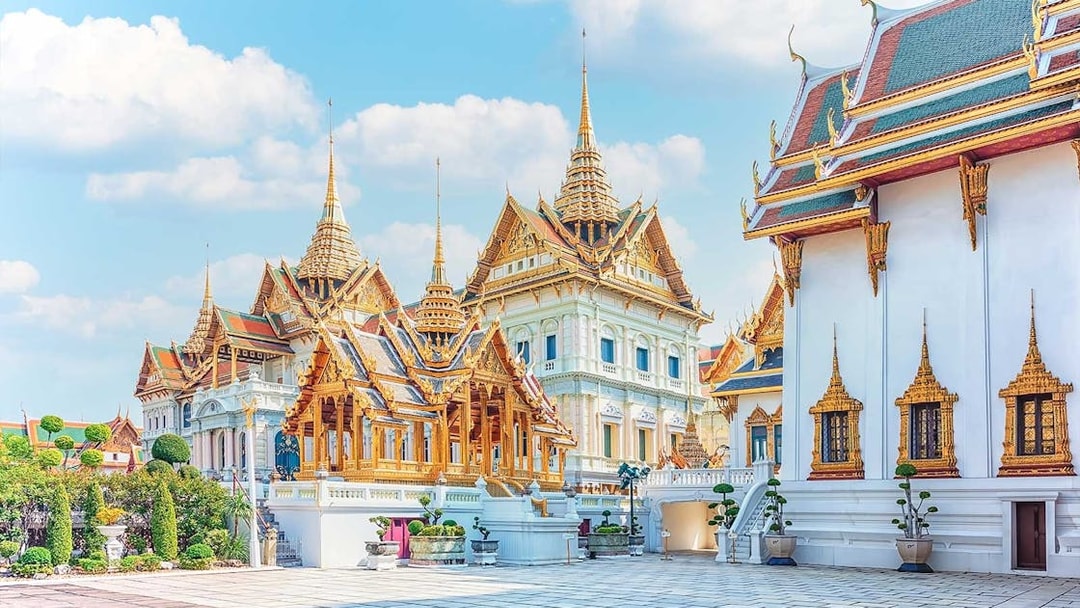 Grand Palace and ornate temples in Bangkok under a clear sky.