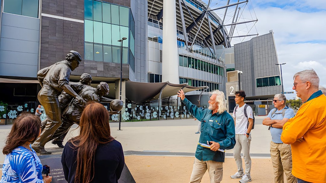 Guide explaining statue to visitors at Melbourne Cricket Ground, Melbourne.