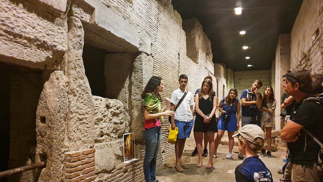 Tour group exploring underground ruins in Naples with a guide explaining historical details.