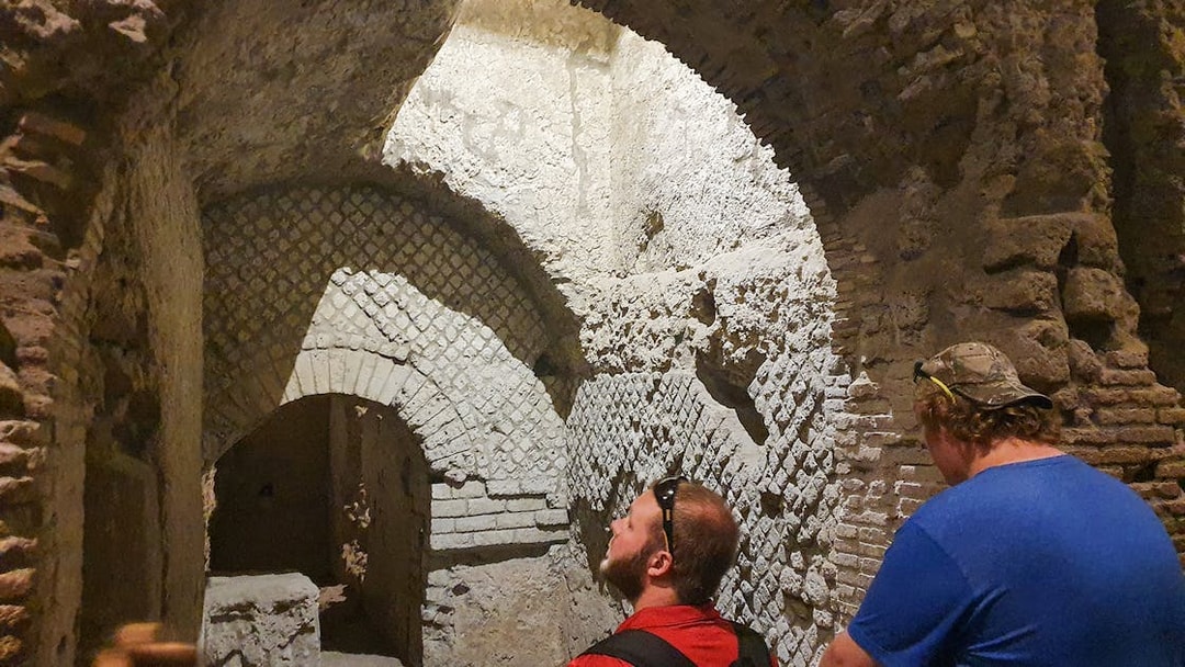 Tourists exploring ancient underground ruins in Naples, Italy during a guided city tour.