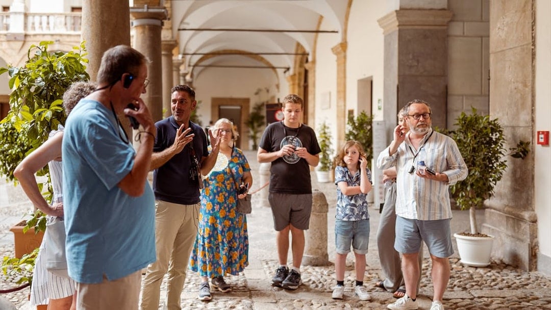 Group listening to guide at Palazzo Dei Normanni courtyard.