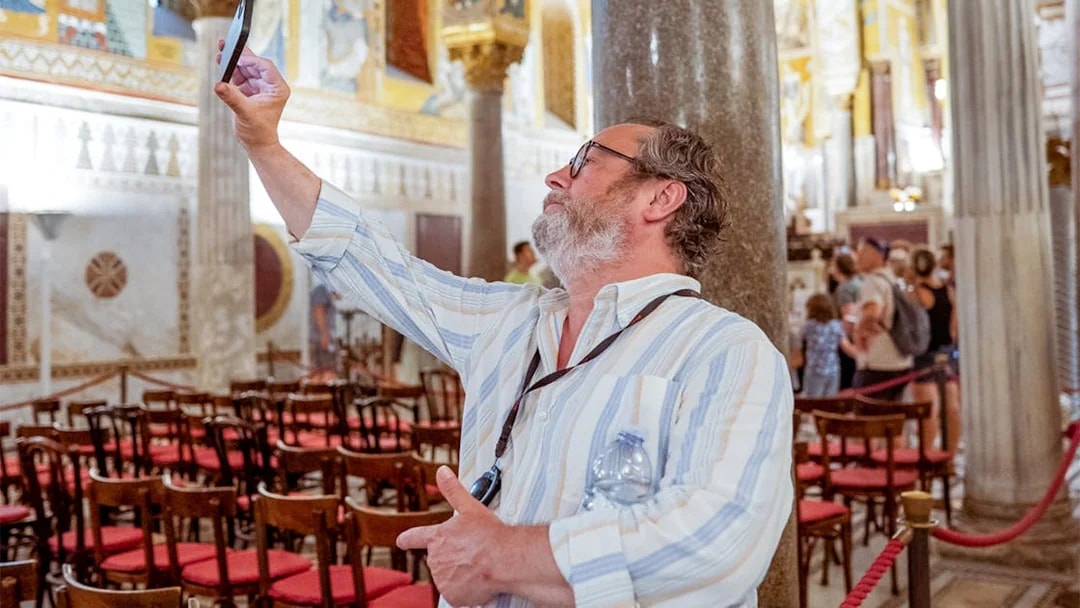 Man taking a photo inside Palazzo Dei Normanni during a guided tour.