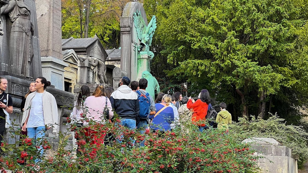 Visitors exploring statues and tombs at Père Lachaise Cemetery, Paris.