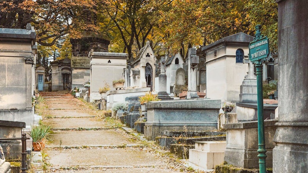 Pathway through tombs at Père Lachaise Cemetery, Paris, with autumn trees overhead.